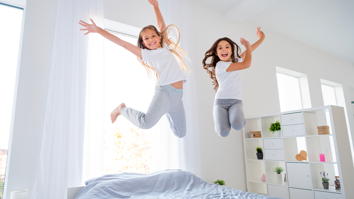 Bambini che saltano su letti singoli moderni