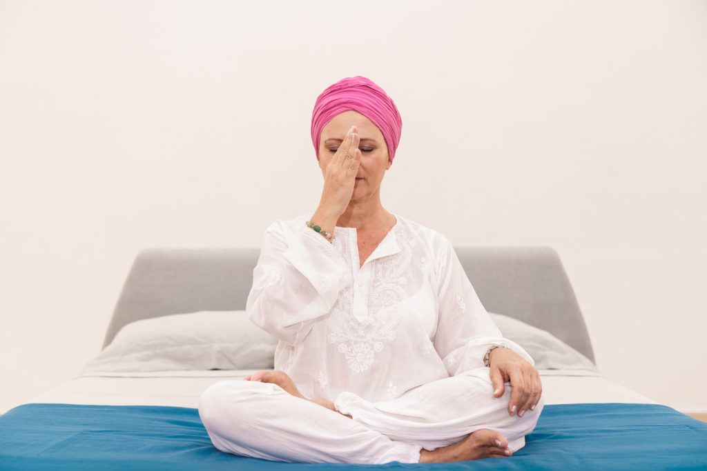 meditazione-tecniche-per-rilassarsi-2 donna su letto che esegue una tecnica di meditazione per rilassarsi respirando alternando le narici
