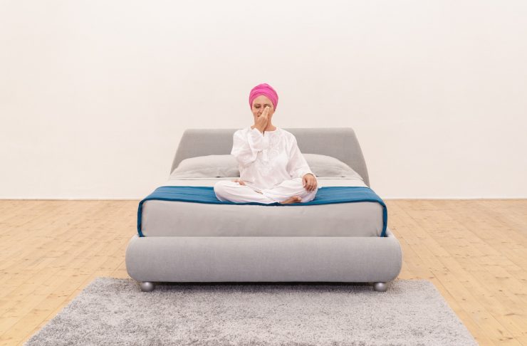 donna su letto che esegue una tecnica di meditazione per rilassarsi respirando alternando le narici