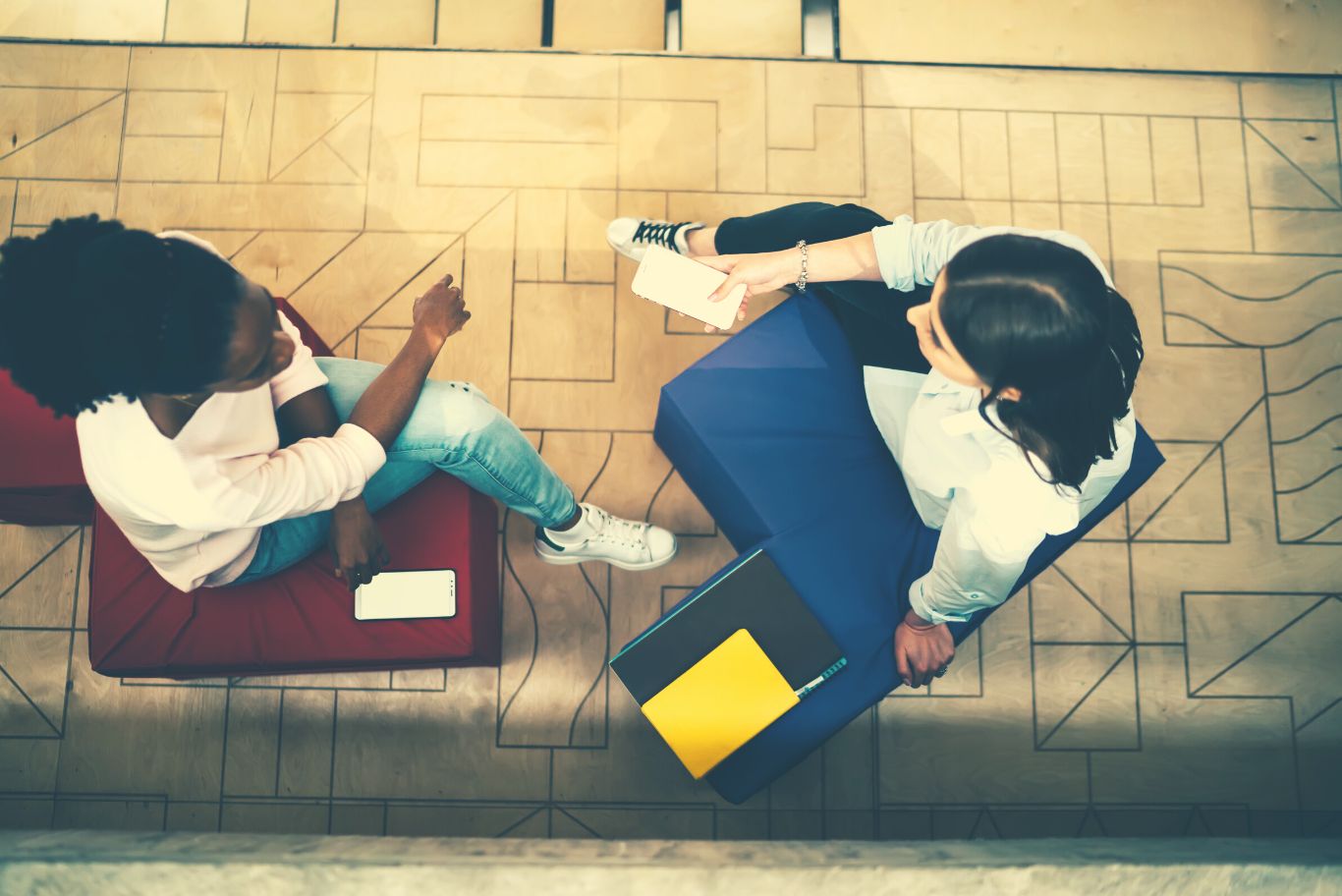 Due ragazze sedute su una poltrona letto blu e su una poltrona letto rossa